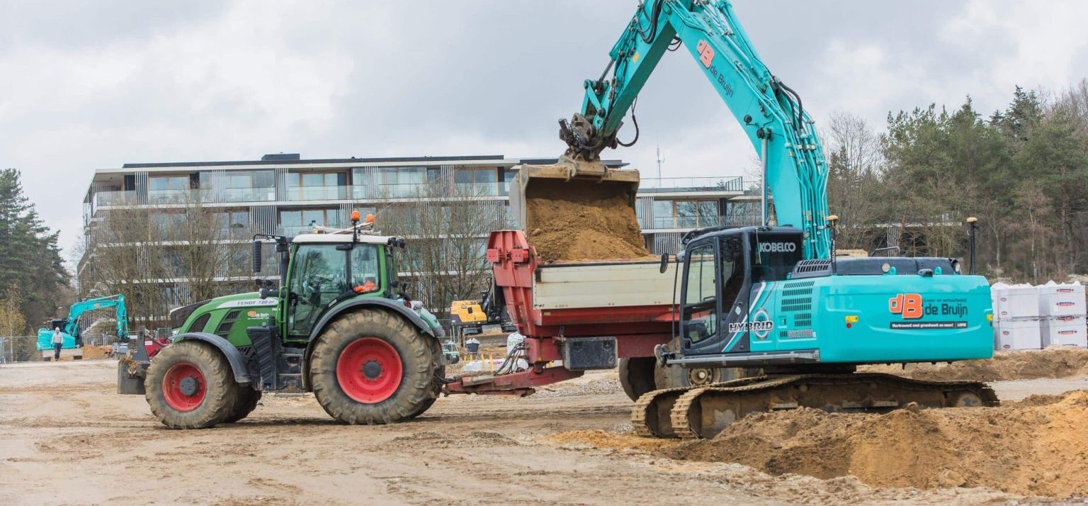 Graafmachine laadt zand in een vrachtwagen bij grondwerk